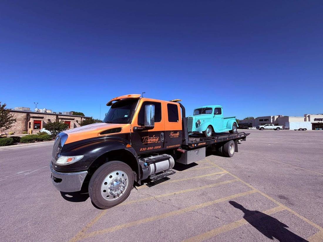 Integrity Towing flatbed hauling a vintage pickup truck