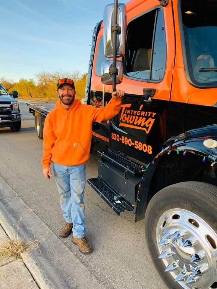 Jerry, co-owner of Integrity Towing, standing beside the company's flatbed truck